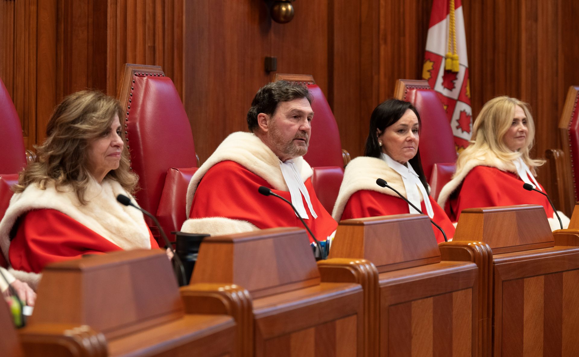 Quatre juges de la Cour suprême en toge rouge, assis au banc.
