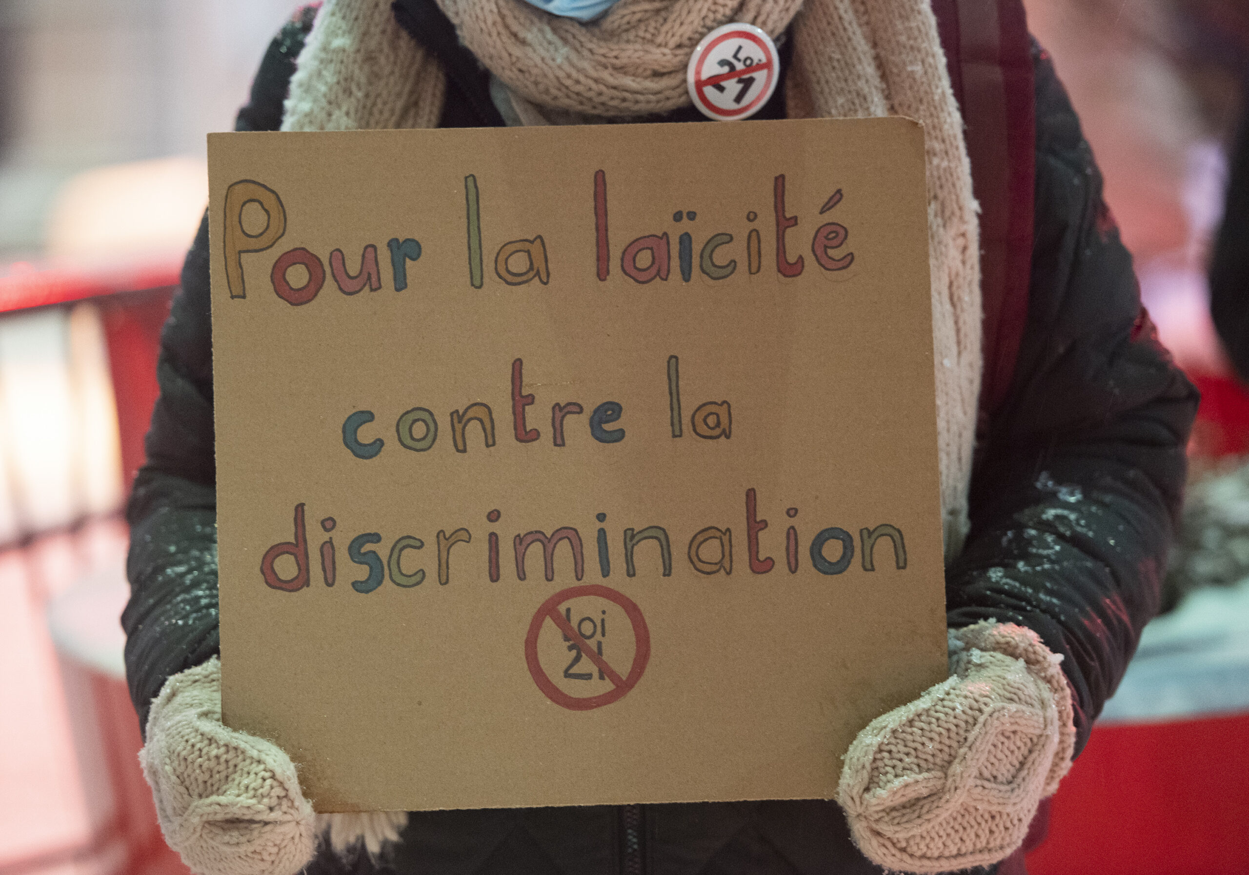 Une femme tient une pancarte lors d’une protestation sur laquelle il est écrit «pour la laïcité, contre la discrimination».