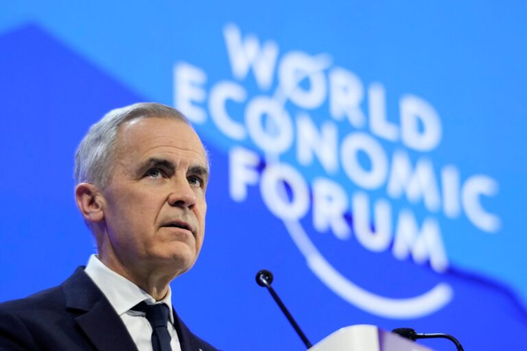 Mark Carney in closeup with the World Economic Forum sign in the background.