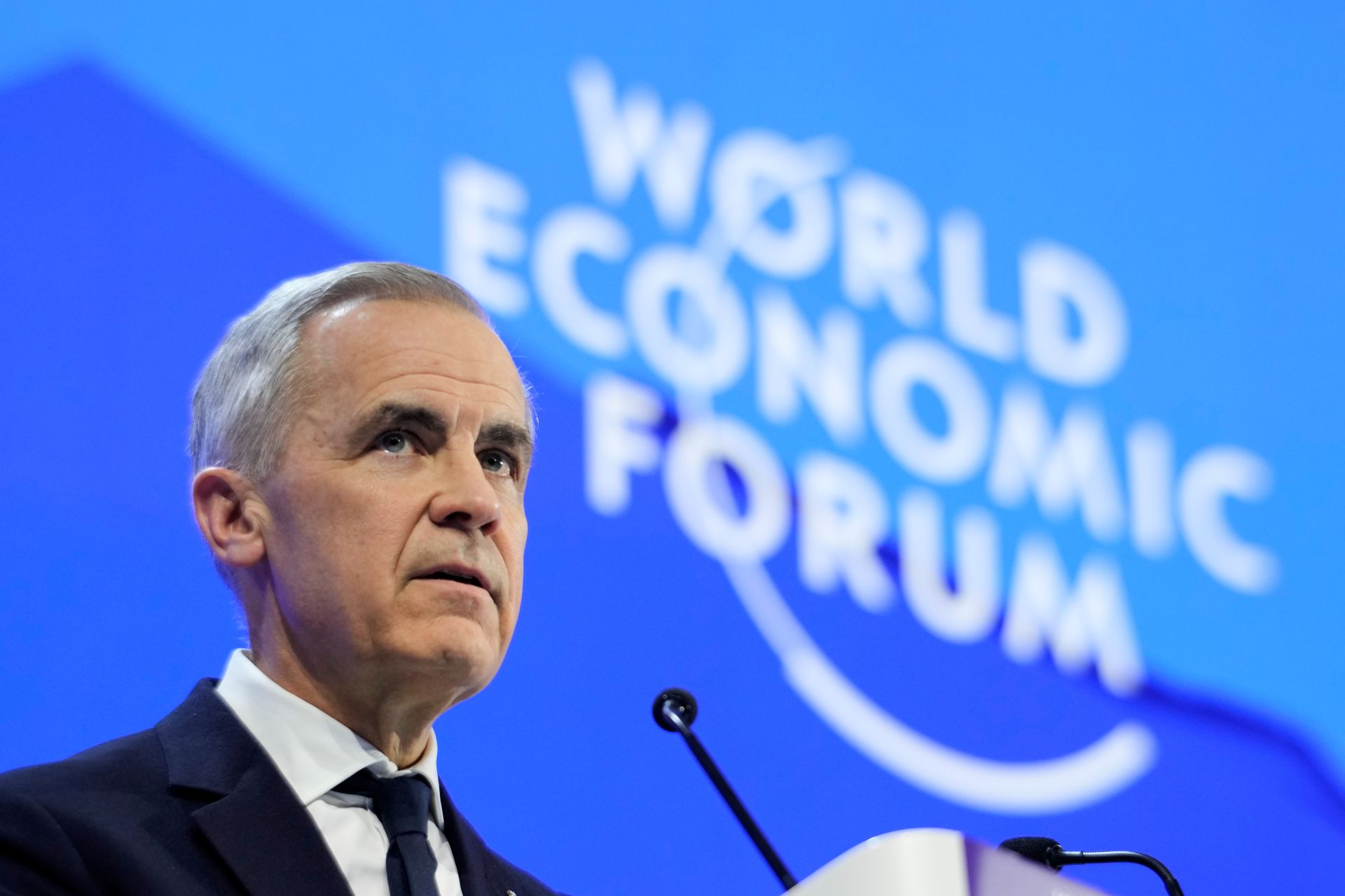 Mark Carney in closeup with the World Economic Forum sign in the background.