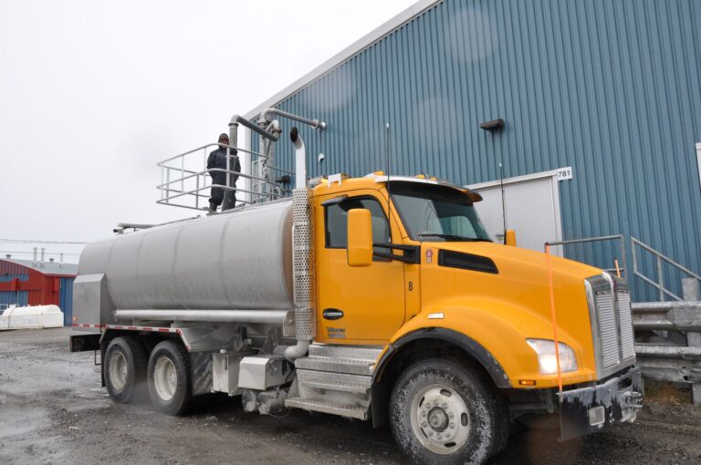A yellow tanker truck loading up on fresh water.
