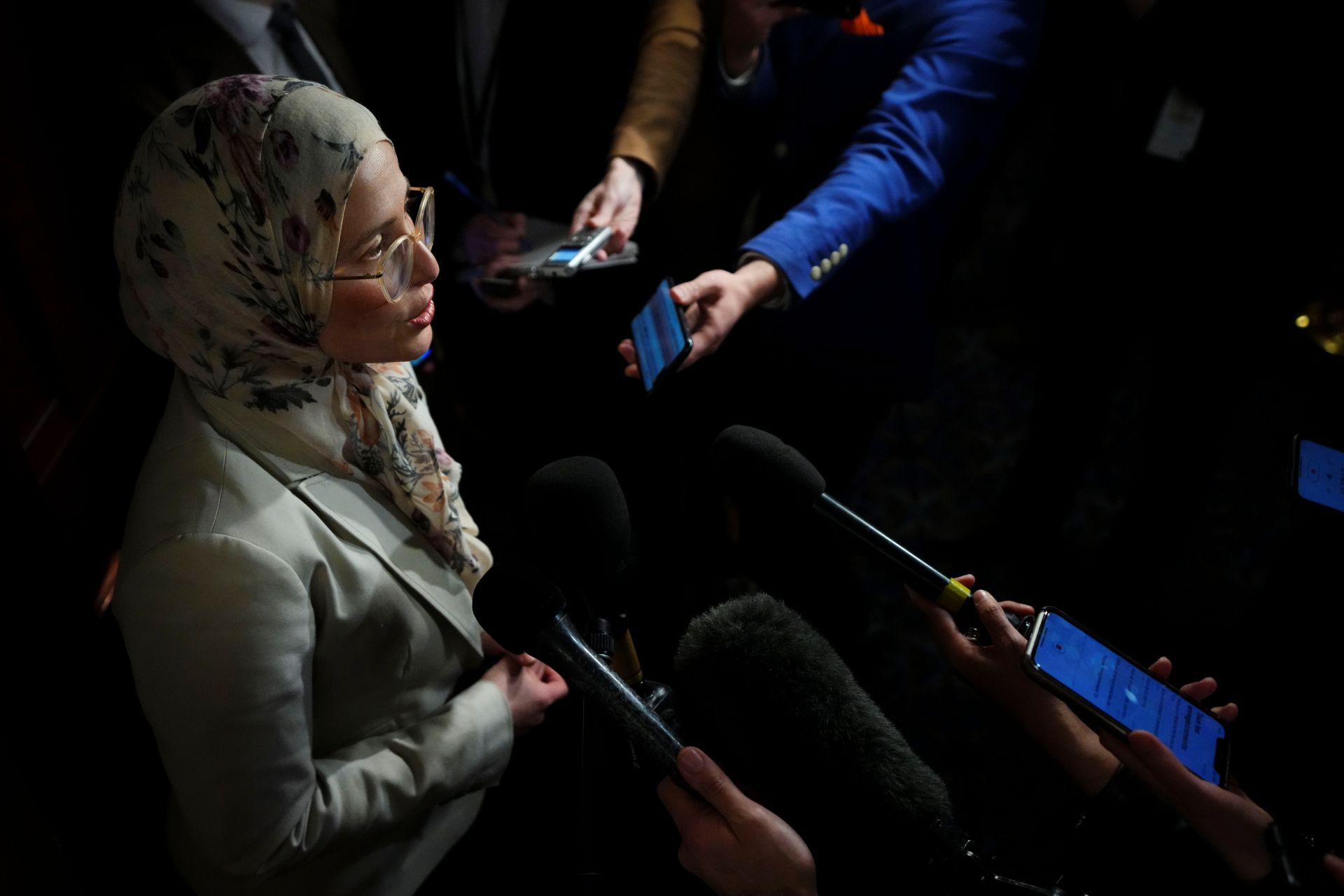Elghawaby speaks in front of an array of arms holding microphones.