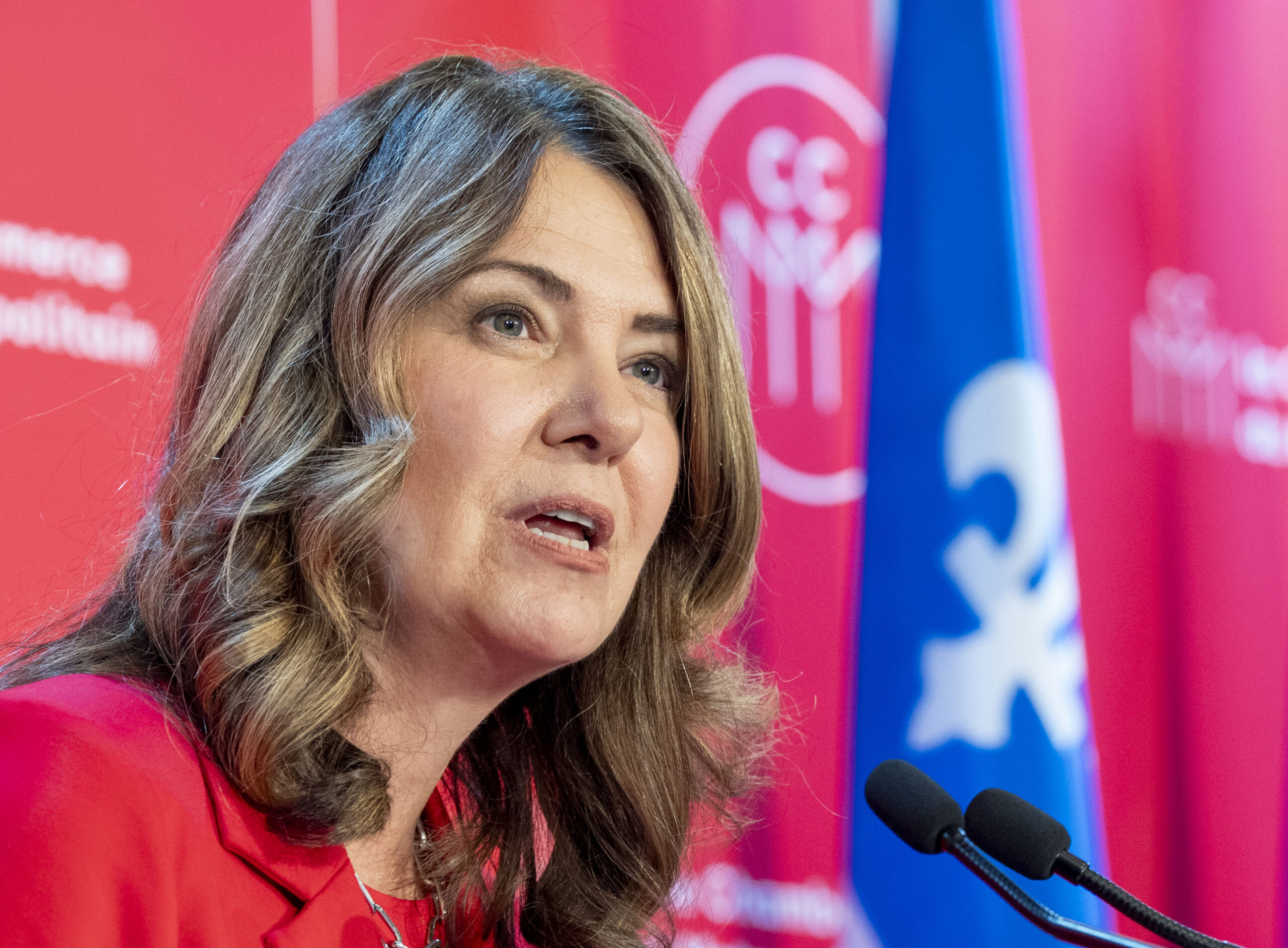 La première ministre de l’Alberta, Danielle Smith, avec le drapeau du Québec en arrière-plan.