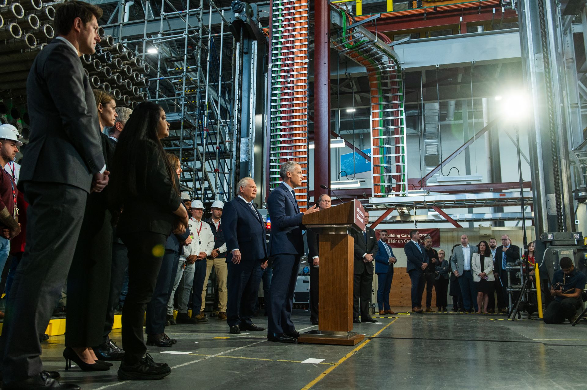 Dozens of people stand around the mechanical room.