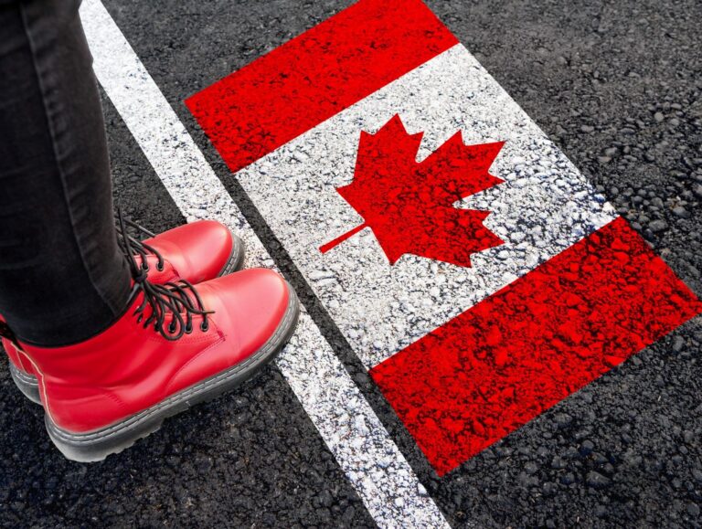 An illustration featuring a person in red boots stands at a metaphorical starting line before a Canadian flag painted onto the pavement.