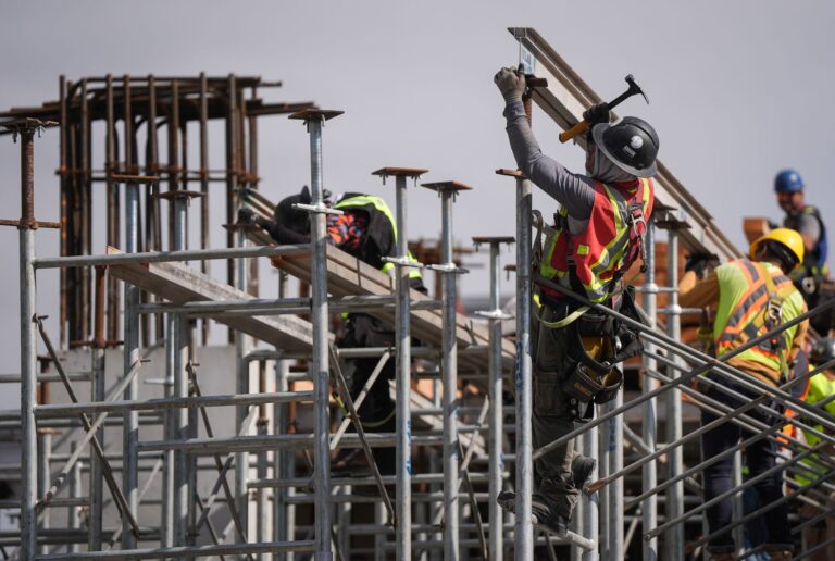 Five men work amid scaffolding and beams.