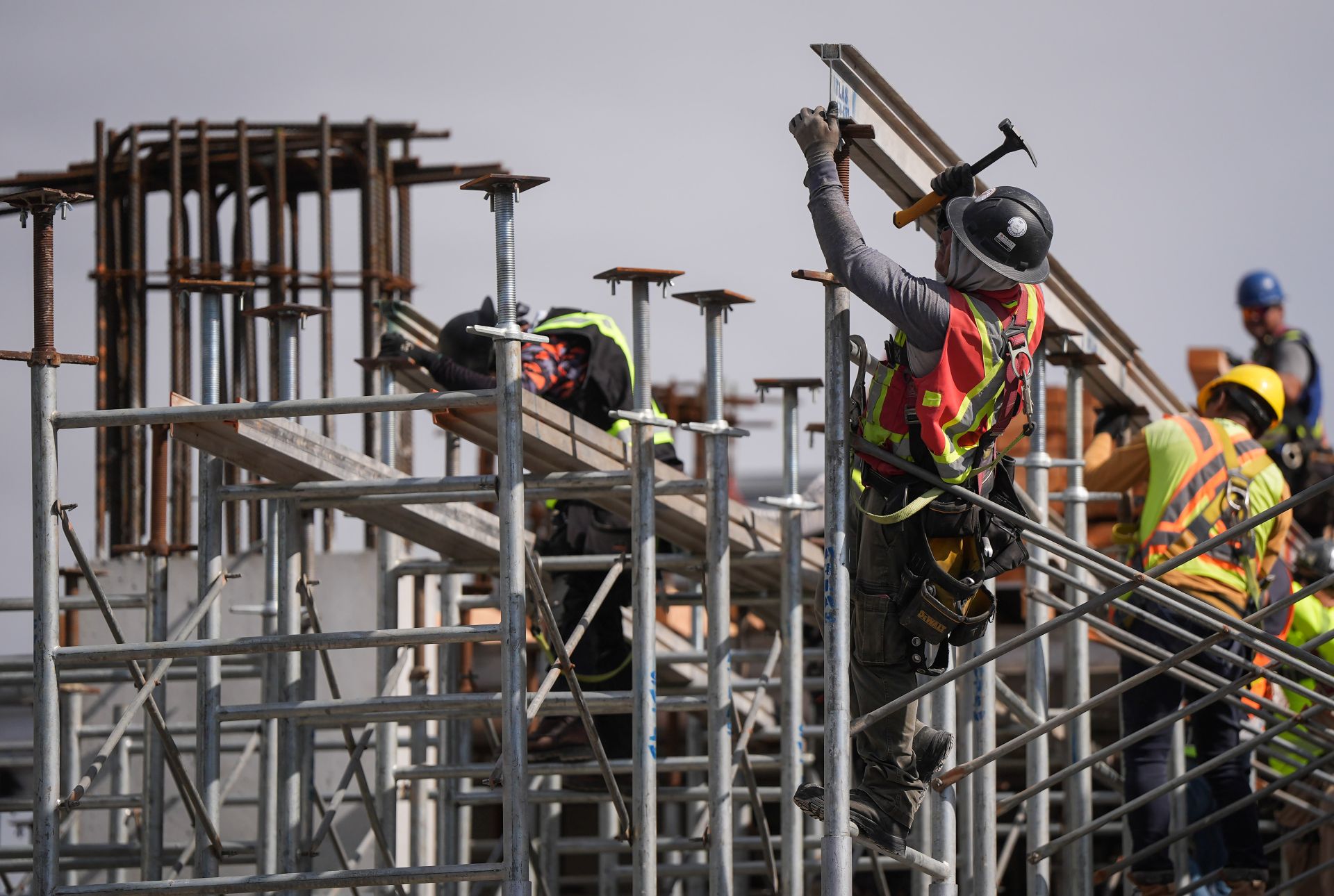 Five men work amid scaffolding and beams.