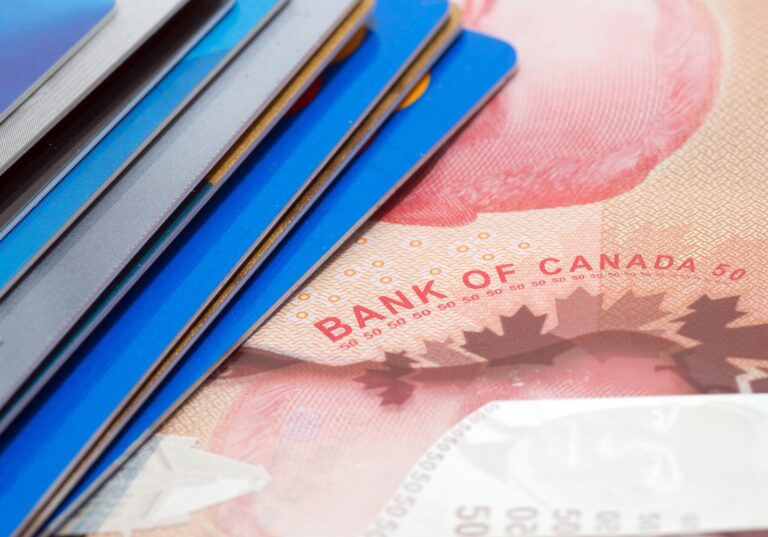 An illustration of some bank cards stacked on top of a red $50-bill with "Bank of Canada" written on it.