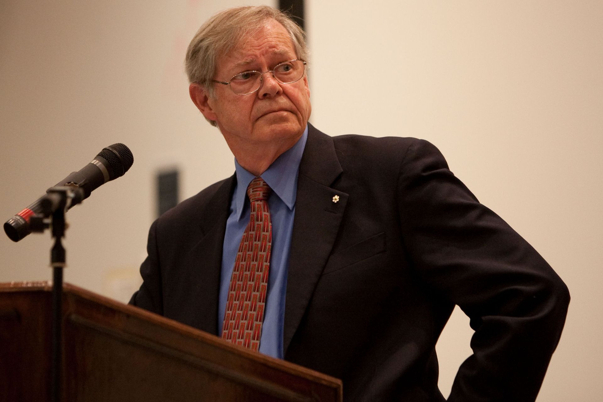 ALT: Thomas Courchene standing at a podium looking offstage.