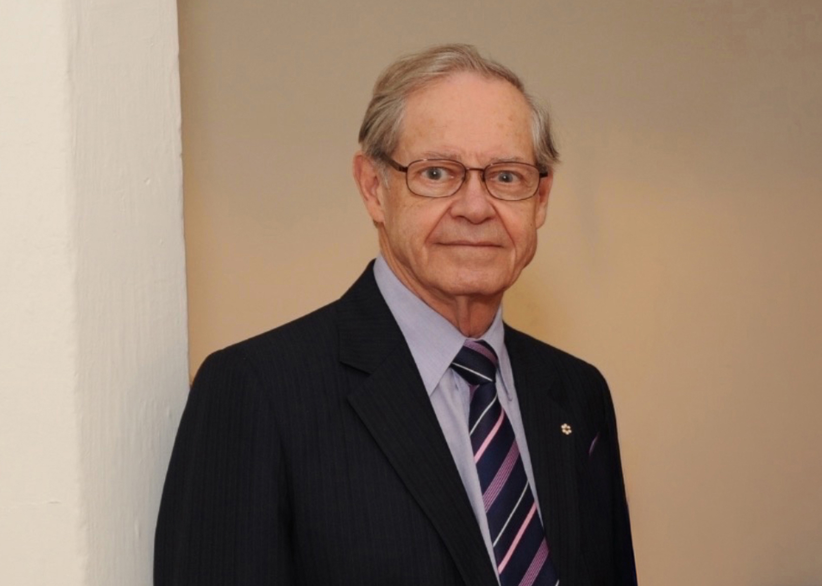 Thomas Courchene in a suit standing for a portrait.