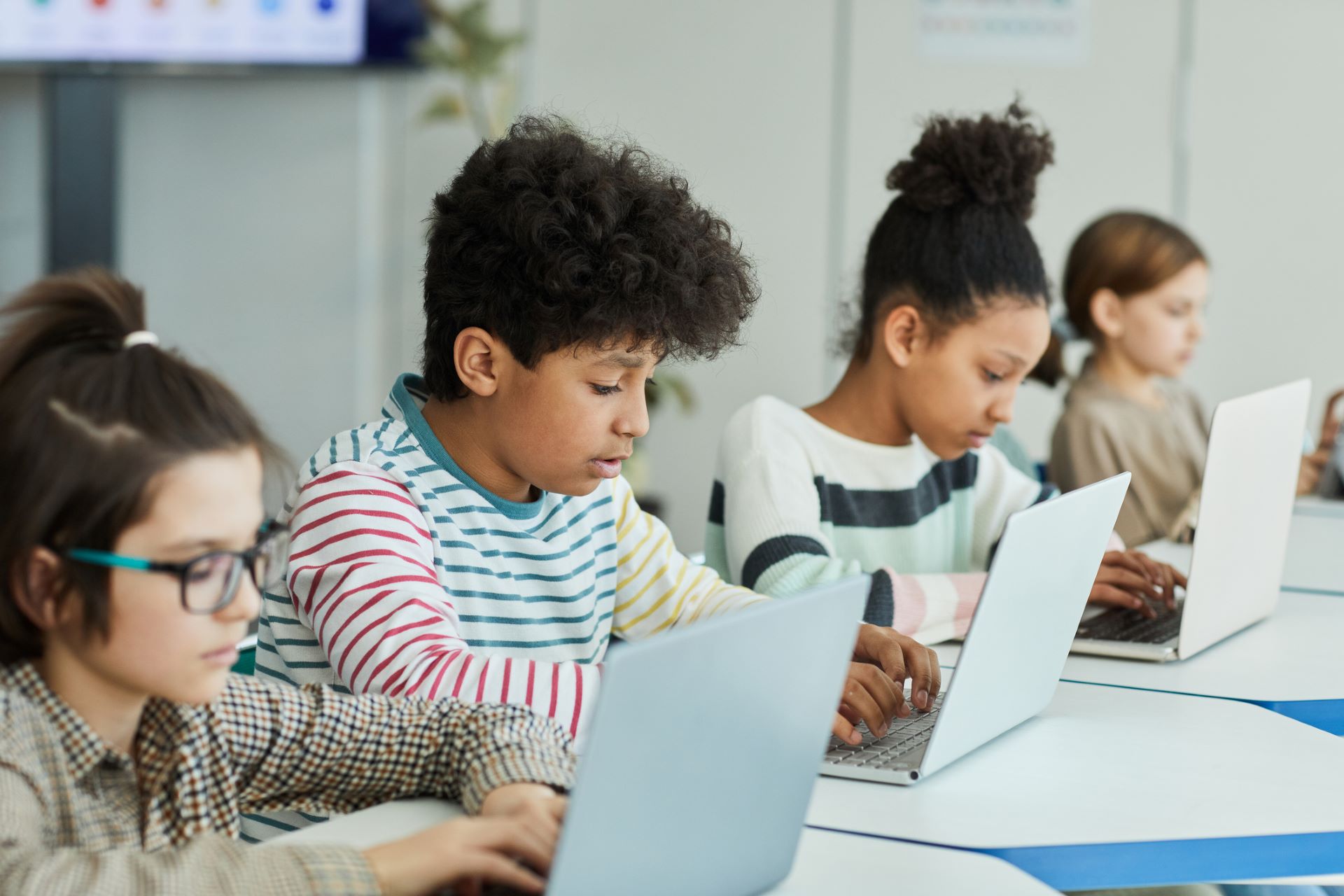 Four young children using laptops sitting at a table side by