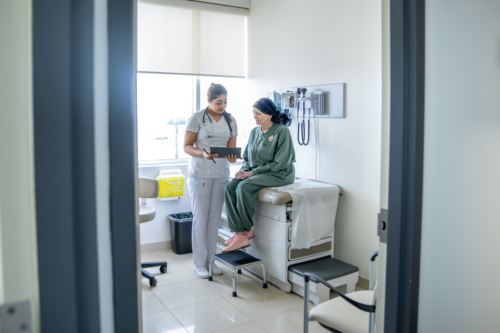 A medical practitioner going over medical information with a patient in an examination room.