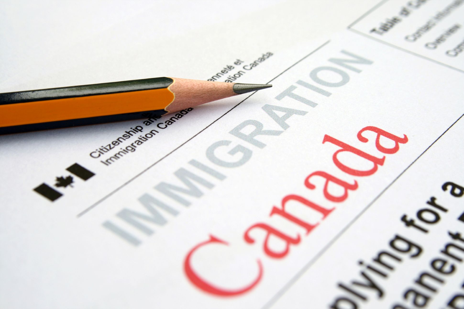 Alt text : Formulaire d’immigration canadienne avec le mot « Canada » en rouge et un crayon posé sur le document.