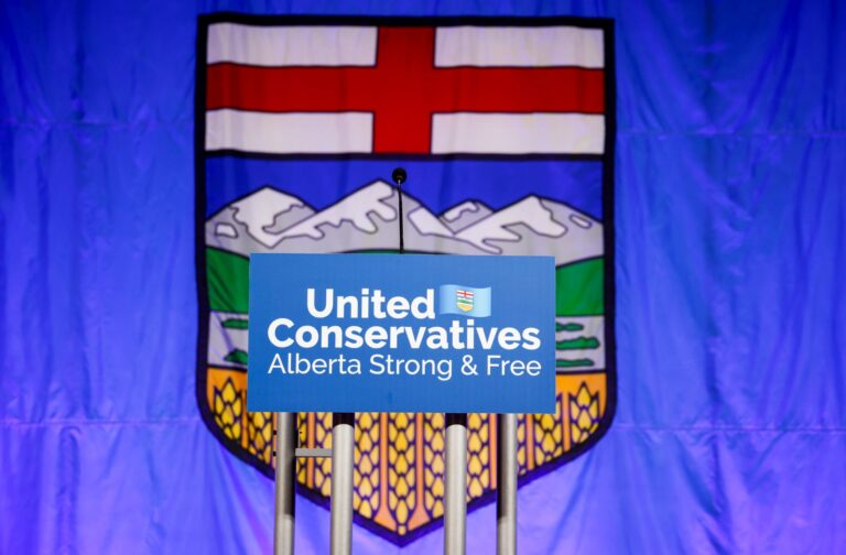 Une pancarte du Parti conservateur uni de l’Alberta posée sur un podium est visible devant le drapeau de l’Alberta.