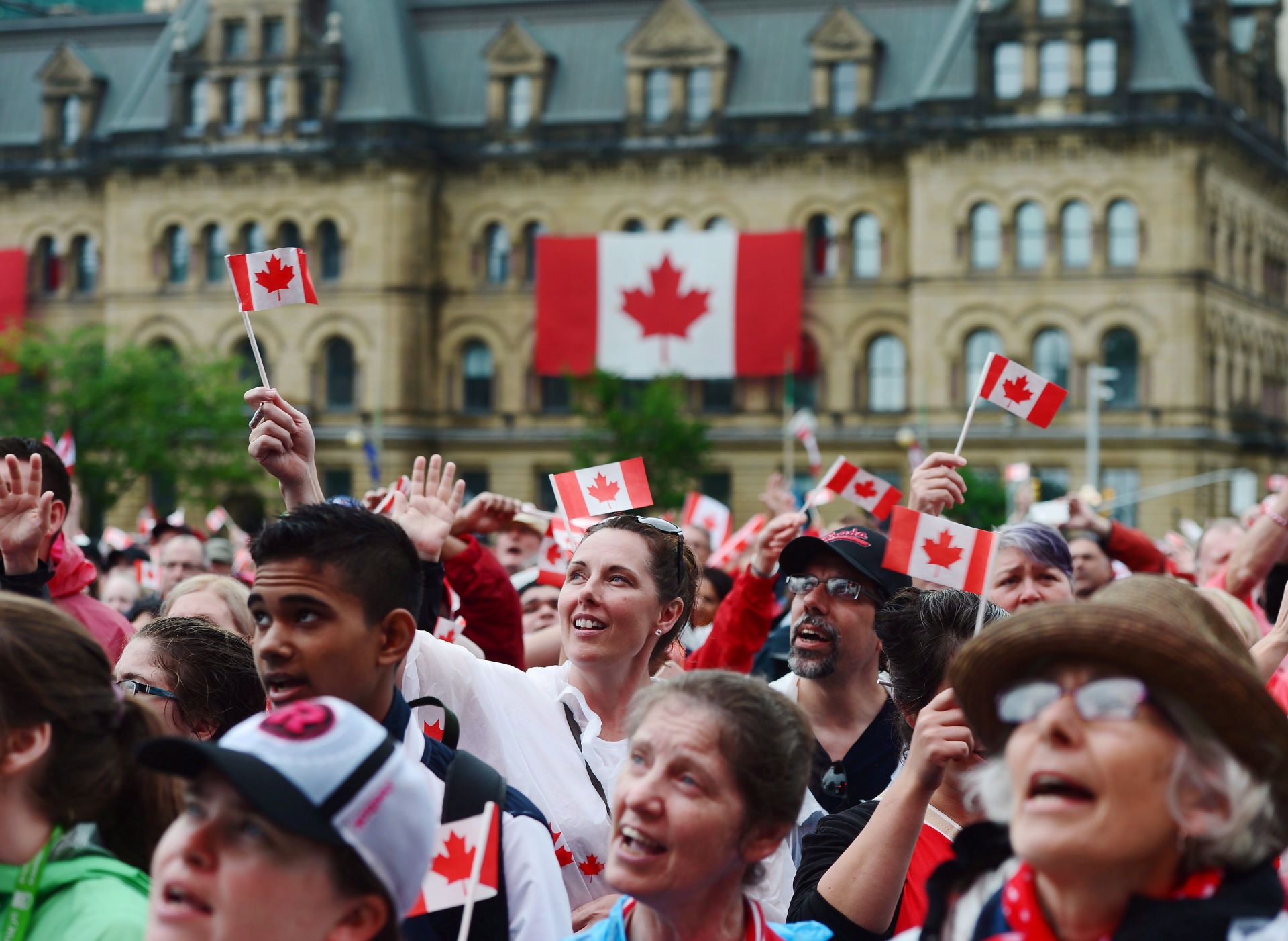 A large crowd waves small Canadian flags.