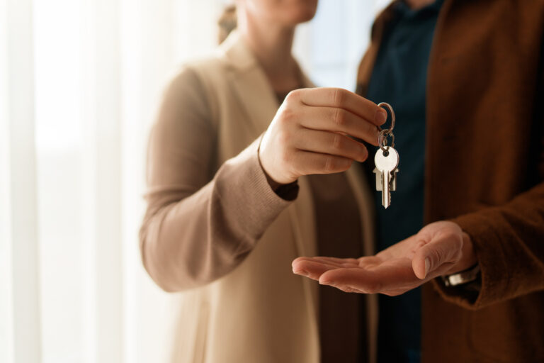 A stock image of a woman placing keys in the hands of a man.