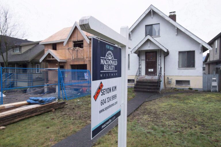 Panneau « À vendre » devant une maison unifamiliale à Vancouver, à côté d’un chantier de construction résidentielle dans un quartier urbain.