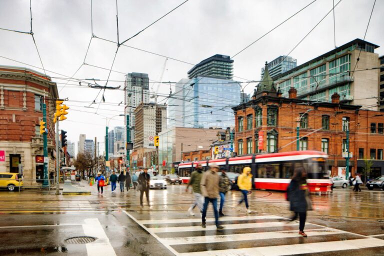 Electric-trolley wires connect overhead as a dozen people cross the street.