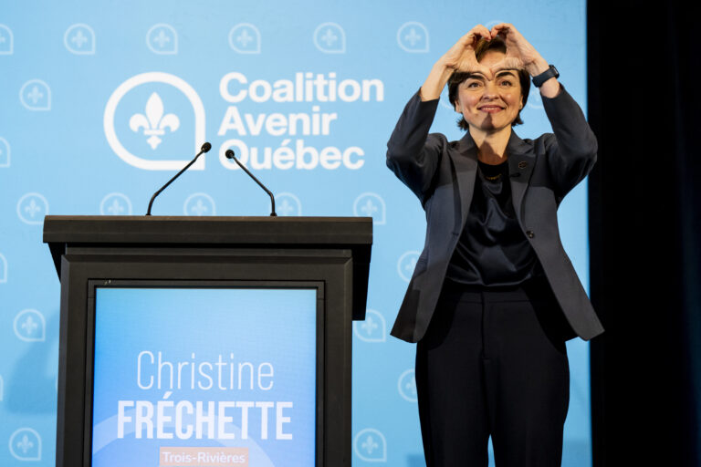 Christine Fréchette est debout et forme un coeur avec ses mains durant une conférence de presse.
