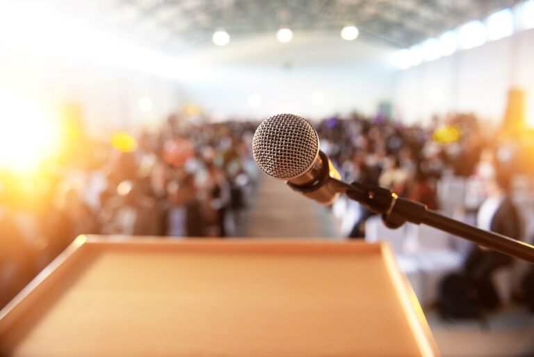 Microphone at a podium in front of an audience.