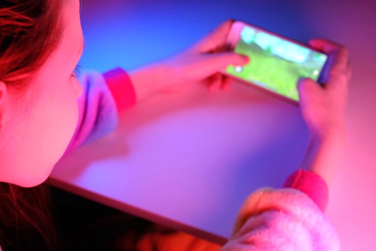 A young girl plays a game on a phone.