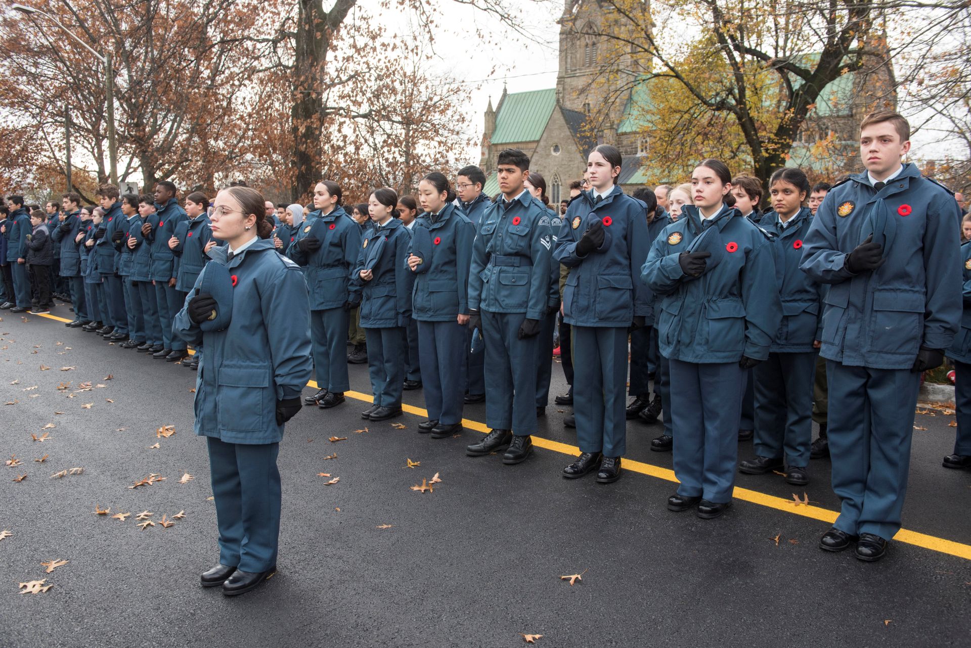 Cadets in formation standing at attention, many with their caps at their hearts.