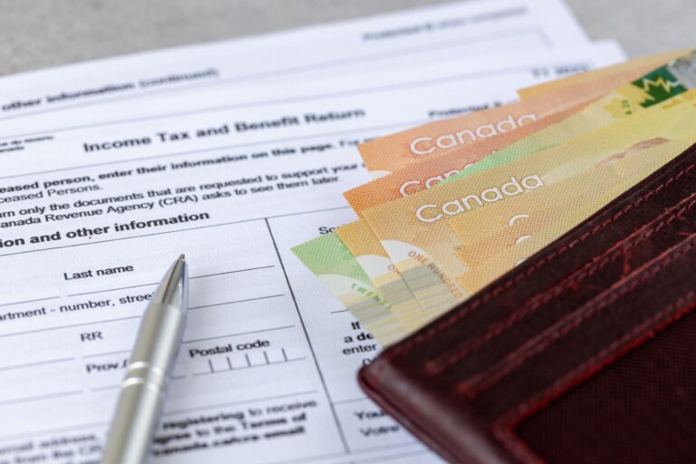 A wallet, with some cash peaking out, sitting on a tax form.