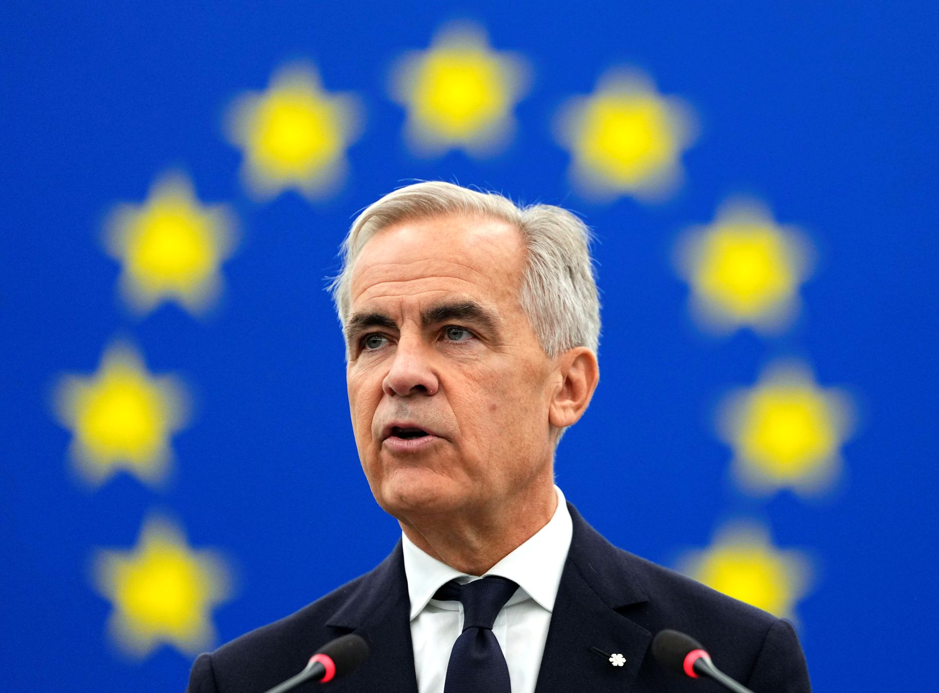 A portrait of Mark Carney surrounded by the yellow stars of the European Union flag.